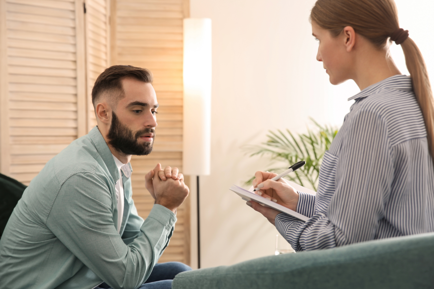Man in therapy session with therapist taking notes